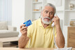 © New Africa - Confused senior man with credit card talking on phone at home. Be careful - fraud