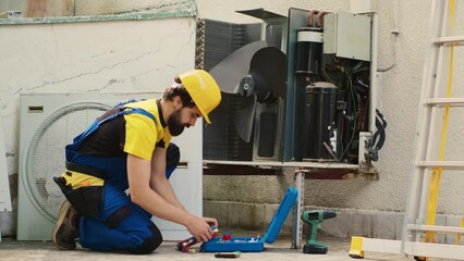 Wall Mural - Skilled engineer commissioned for routine hvac system maintenance, assembling manometer before starting work. Repairman looking to find refrigerant leaks leading to reduced cooling efficiency