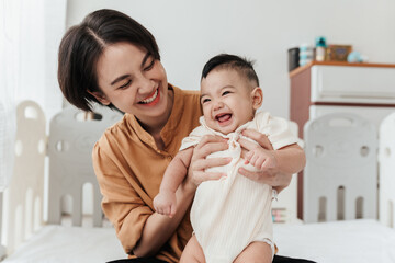 Happiness Asian mother conference and playing with adorable her son looking at camera. Asian mom lifting and playing newborn baby. Happy asian family healthcare love together mother’s day concept.