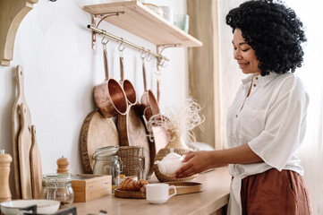 african american woman pouring tea in cup at kitchen