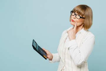 Wall Mural - Side view minded successful employee business woman 50s wearing white classic suit glasses formal clothes using calculator isolated on plain pastel light blue background. Achievement career concept.