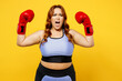 Young chubby overweight plus size big fat fit woman wear blue top red gloves warm up training boxing raise up hands scream isolated on plain yellow background studio home gym. Workout sport concept.