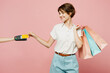 © ViDi Studio - Young woman in casual clothes holding shopping paper package bags wireless bank payment terminal process acquire credit card isolated on plain pink color background. Black Friday sale buy day concept