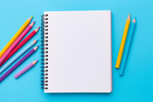 Top View Of Empty Notebook With Colorful Crayon Pencils On Pastel Blue Background