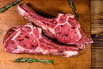 Wall Mural - Raw ribeye steak, spices and rosemary on cutting board. Top view