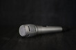 Silver microphone place on black table in the dark corner. Microphone can amplify the sound lounder for the singer, orator, politician, complainant, teacher, MC and announcer.