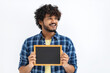 © kucherav - Happy Asian man with curly hair holds a small empty chalkboard looking away and smiles friendly standing on a white background