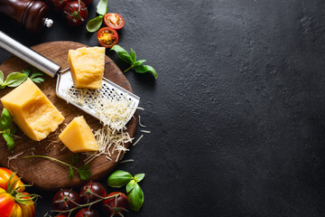 Canvas Print - Cooking background with ingredients for preparation healthy food parmesan cheese, basil leaves, cherry tomato and olive oil on dark table top view, copy space