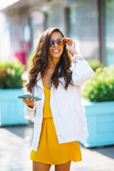 Wall Mural - Happy woman with shopping bags enjoys good weather in sunny city. Sale, shopping, lifestyle concept. Concept of consumerism.