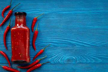 Wall Mural - Bottle of spicy sauce tabasco with red hot chili pepper, top view