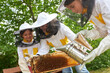 © Robert Kneschke - Smiling female apiarist teaching about honeycomb frame to girls