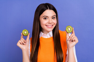 Sticker - Photo of adorable positive girl beaming smile hands hold two kiwi halves isolated on violet color background