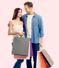 Wall Mural - Happy couple with shopping bags, standing close and looking to each other with smile. Caucasian models in love, holiday sales, shop, retail, consumer concept.