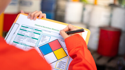 Wall Mural - a safety officer is checking on the hazardous material checklist form with chemical storage area at 