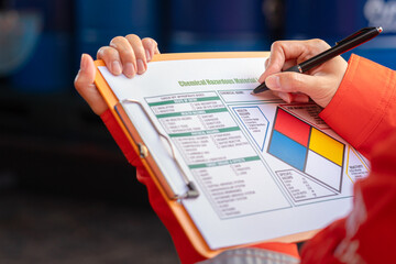 Wall Mural - a safety officer is checking on the hazardous material checklist form with chemical storage area at 