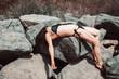 The body of a young woman in a bathing suit, lying on the rocks, near the sea. Murdered woman- concept.