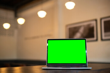 Wall Mural - Mockup of laptop computer with empty screen on table side the window in the coffee shop at the cafe,green screen