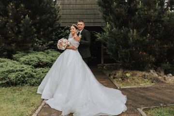 the bride and groom pose against the background of green trees. Wedding walk in nature in the park