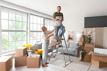 Wall Mural - Mature couple with ceiling lamp in room on moving day