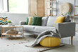 © Pixel-Shot - Cozy grey sofa, coffee table and pouf with soft blanket in interior of living room