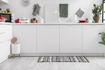Wall Mural - Interior of modern kitchen with stylish rug, trash bin and white counters