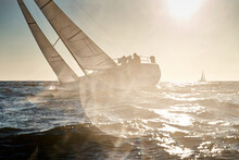 The View Through The Spray Of How The Sailboat Is Heeling At Sunset, Boat Roll, Splashes Shine In The Sun, Sailors On The Board