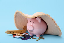 Piggy Bank With Wicker Hat, Wooden Toy Airplane And Credit Cards On Blue Background. Concept Of Savings For Travel