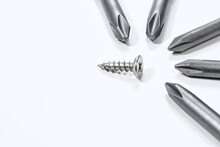 Steel Industrial Screw Surrounded By Screwdrivers Tips.