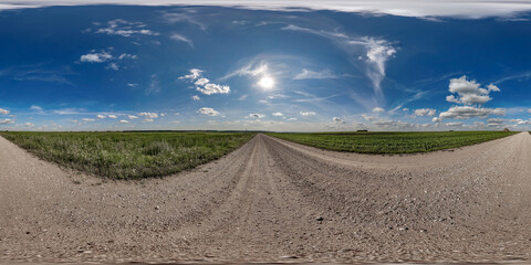 Wall Mural - 360 hdri panorama on wet gravel road with marks from car or tractor tires with clouds on blue sky in equirectangular spherical  seamless projection, skydome replacement in drone panoramas
