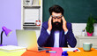 © Svitlana - Tired stressed teacher suffering from headache sitting at desk in classroom. University professor thinking about problems. Exhausted male student feeling migraine after huge load of computer working.