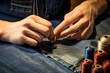 hands sewing a button on denim fabric