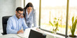 Business man and woman sitting in front of laptop and working together on a project, discussing business strategy that aims to produce results for a company. Panoramic view, copy space.