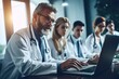 © Bojan - Group of healthcare workers using laptop while having a meeting in the office.