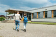 © Elena Medoks - Back to school. A caring father escorts the children to school for the start of classes. Parental care for children. Beginning of the school year.