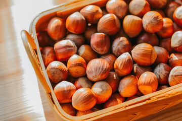 Wall Mural -  Hazelnuts in a basket on a wooden table. Fresh harvest of hazelnuts. Farmed organic ripe hazelnuts. 