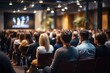 © tanatat - Business and entrepreneurship symposium. Speaker giving a talk at business meeting seminar. Audience in conference hall. Rear view of unrecognized participant in audience, Generative AI