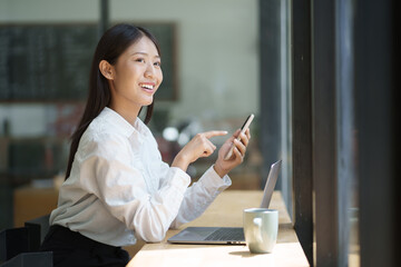 Wall Mural - Young adorable businesswoman using her smartphone during the break after working in her office room.