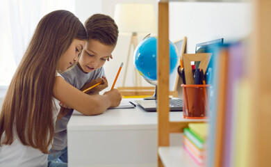 cute focused brother and sister drawing with pencils. portrait of kids sitting at desk writing in no
