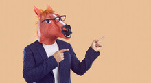 Man Wearing Business Suit, Funny Silly Animal Masquerade Horse Mask And Eyeglasses Standing Isolated On Beige Background And Pointing His Index Fingers Sideways To Show Something On Copy Space Side