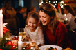 © Anoo - Winter holidays and people concept - mother and daughter at the table celebrating christmas and new year. Home holiday. Blurred background. Selective focus.