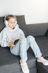 Wall Mural - Little girl with headphones and tablet  at home