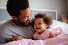 Happy Loving Young Black Dad Holding Adorable Mixed Race Baby Daughter Having Fun In Bed At Home. Smiling African Father Playing With Cute Funny Infant Child Girl Waking Up In Bedroom In The Morning