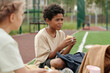 © pressmaster - Cute hungry African American boy in casualwear eating sandwich or some other snack for lunch while sitting among his classmates or friends