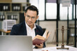 © NINENII - Legal counsel reading a book legislation at desk in office.