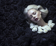 Fashion Editorial Concept. Stunning Beautiful Blond Woman Surround Lying Sleeping On Blooming Black White Rose Flowers Floral Like Angel. Dynamic Composition And Dramatic Lighting

