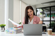 © bongkarn - A cheerful Asian businesswoman looking at her laptop screen with an excited face