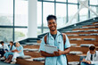 © Drazen - Happy black medical student in amphitheater looking at camera.
