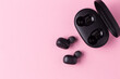 Close-up black wireless headphones on pink isolated background.