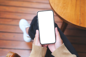 top view mockup image of a woman using and holding mobile phone with blank screen