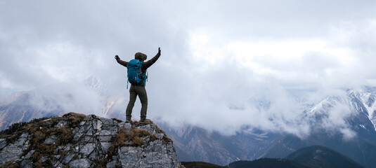 Wall Mural - Woman hiker enjoy the view on mountain top cliff edge face the snow capped mountains in tibet